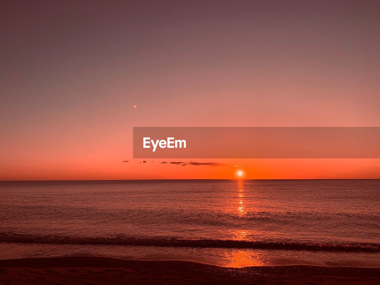 Scenic view of sea against dramatic sky during sunset