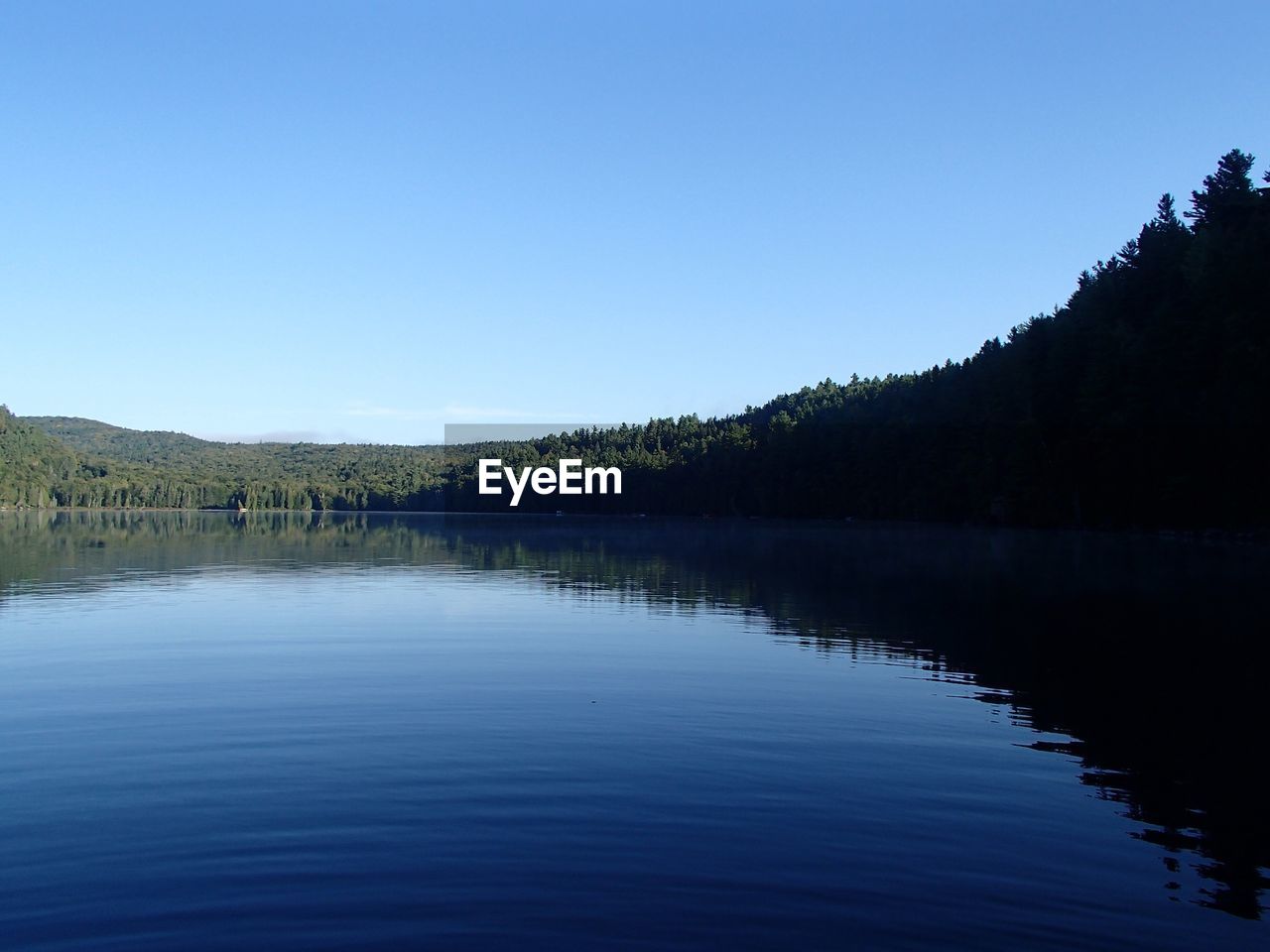 Scenic view of lake against clear blue sky