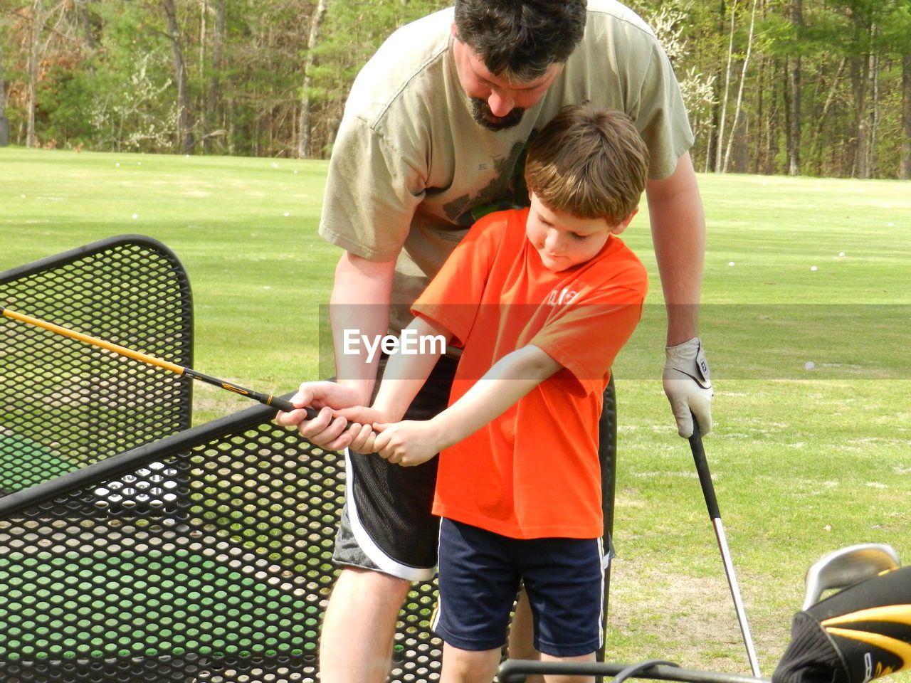 Father and son practicing golf on field