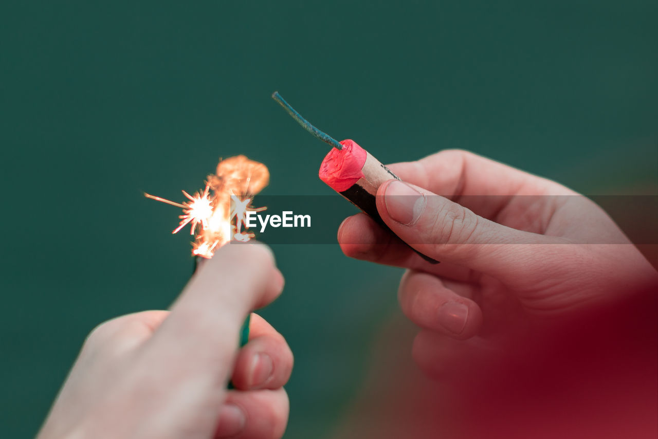 Cropped image of hands holding firecracker