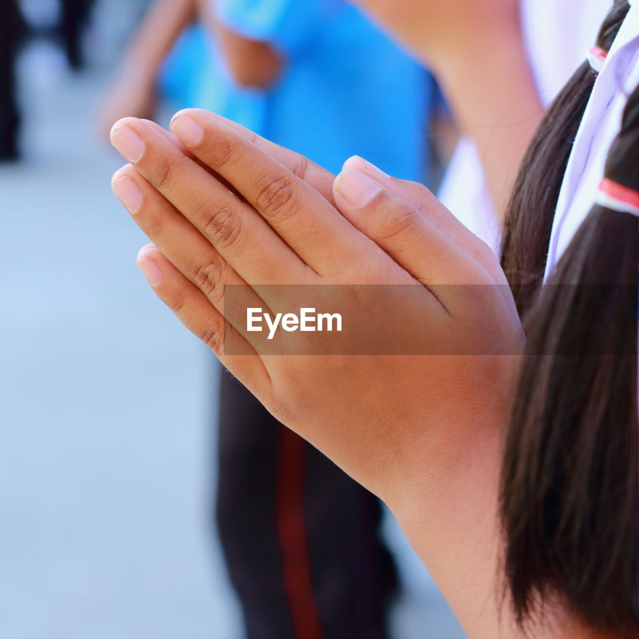 Midsection of schoolgirl standing in prayer position