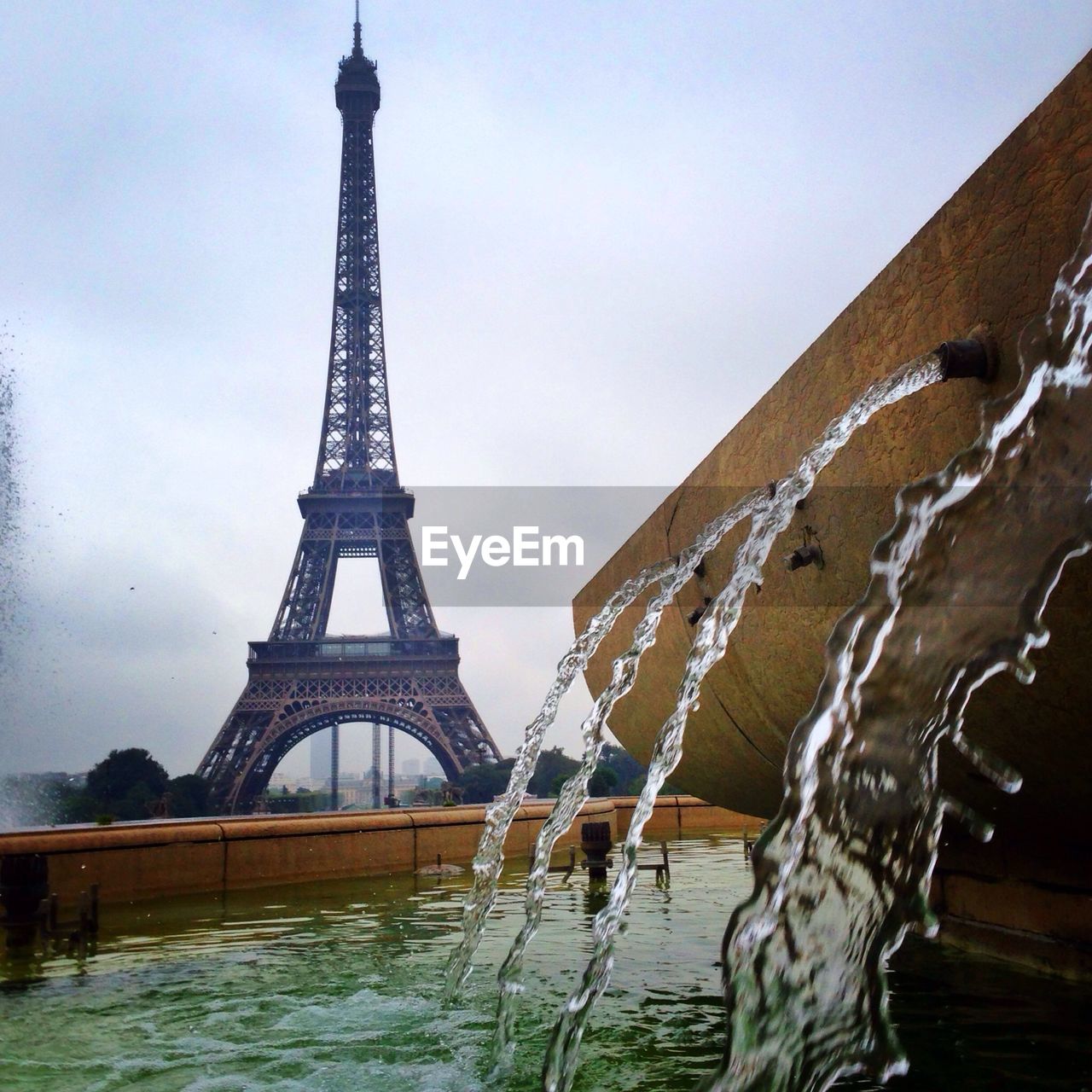 Close-up of falling water at fountain against eiffel tower