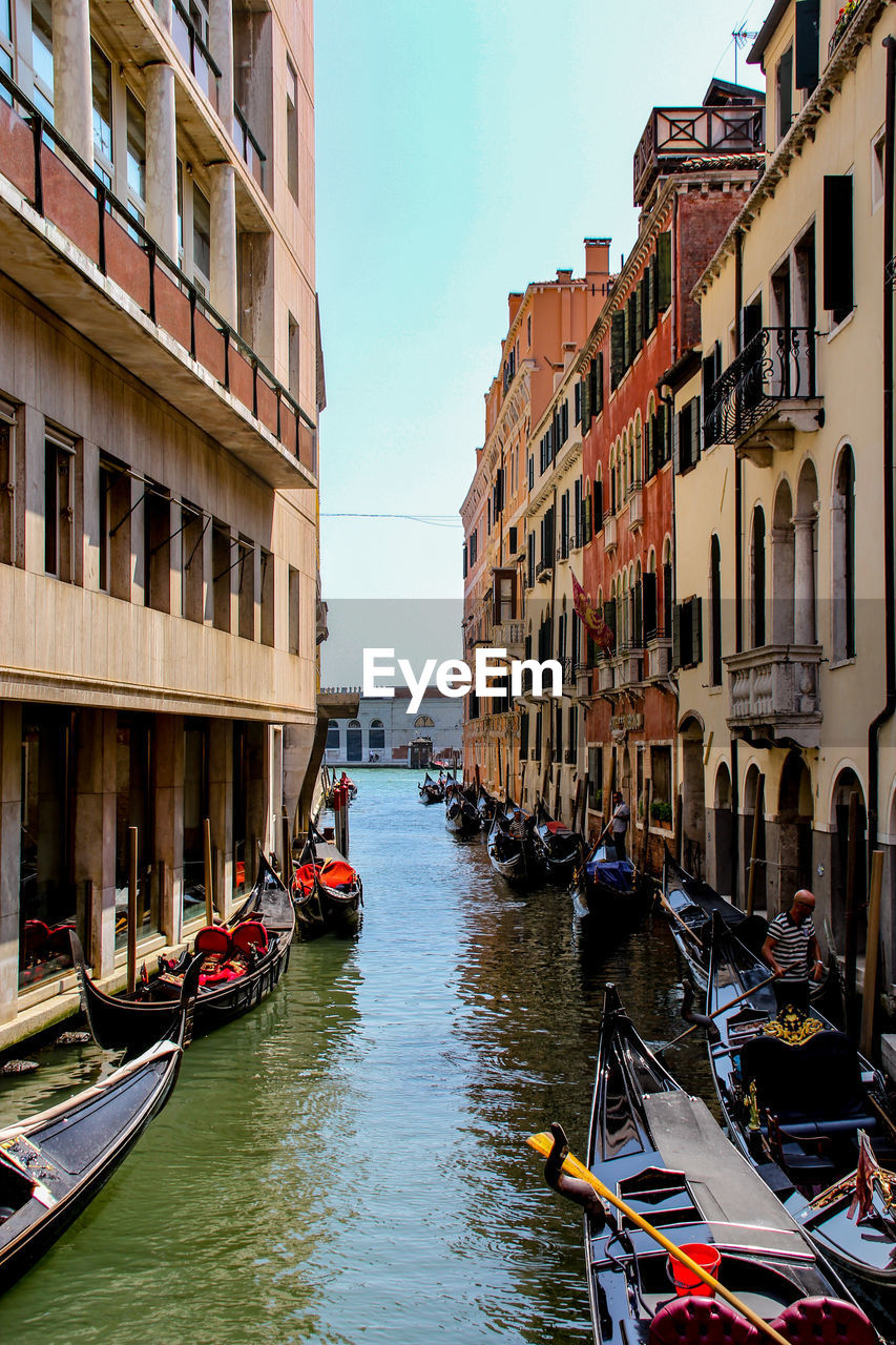 BOATS MOORED IN CANAL BY BUILDINGS IN CITY