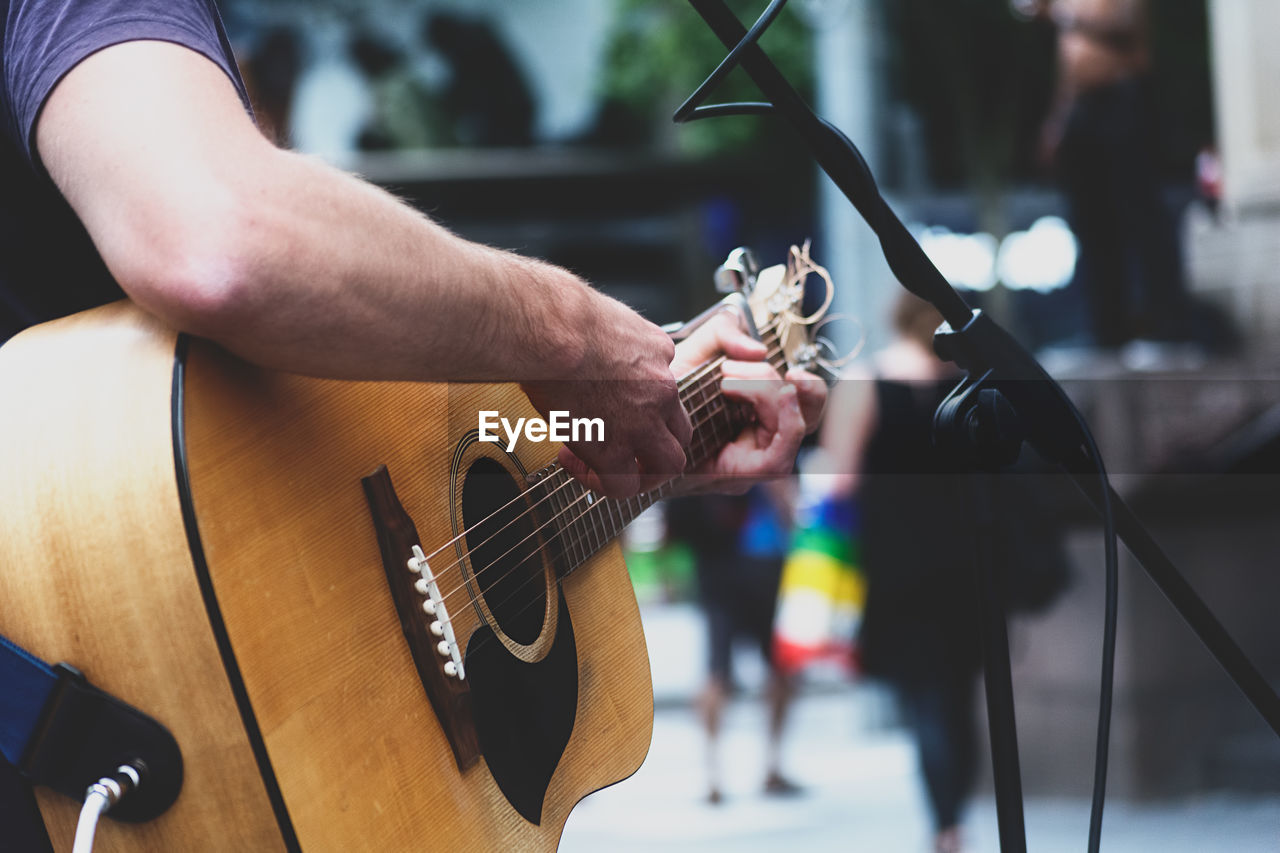 Cropped image of man performing with acoustic guitar on street