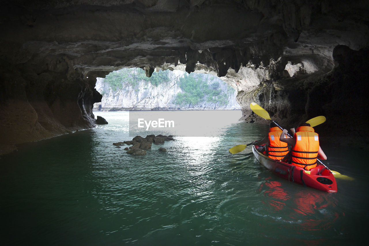 Rear view of people kayaking in cave