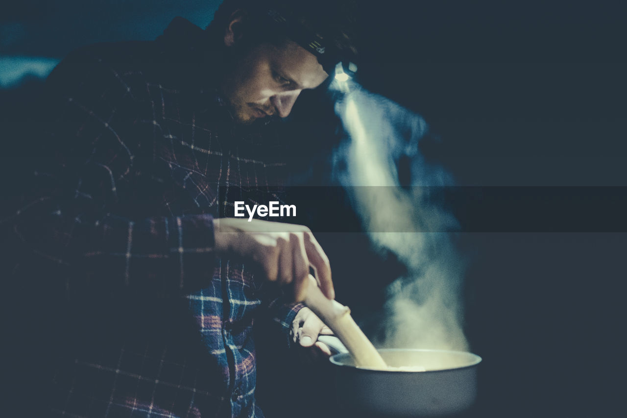 Side view of man preparing food at night