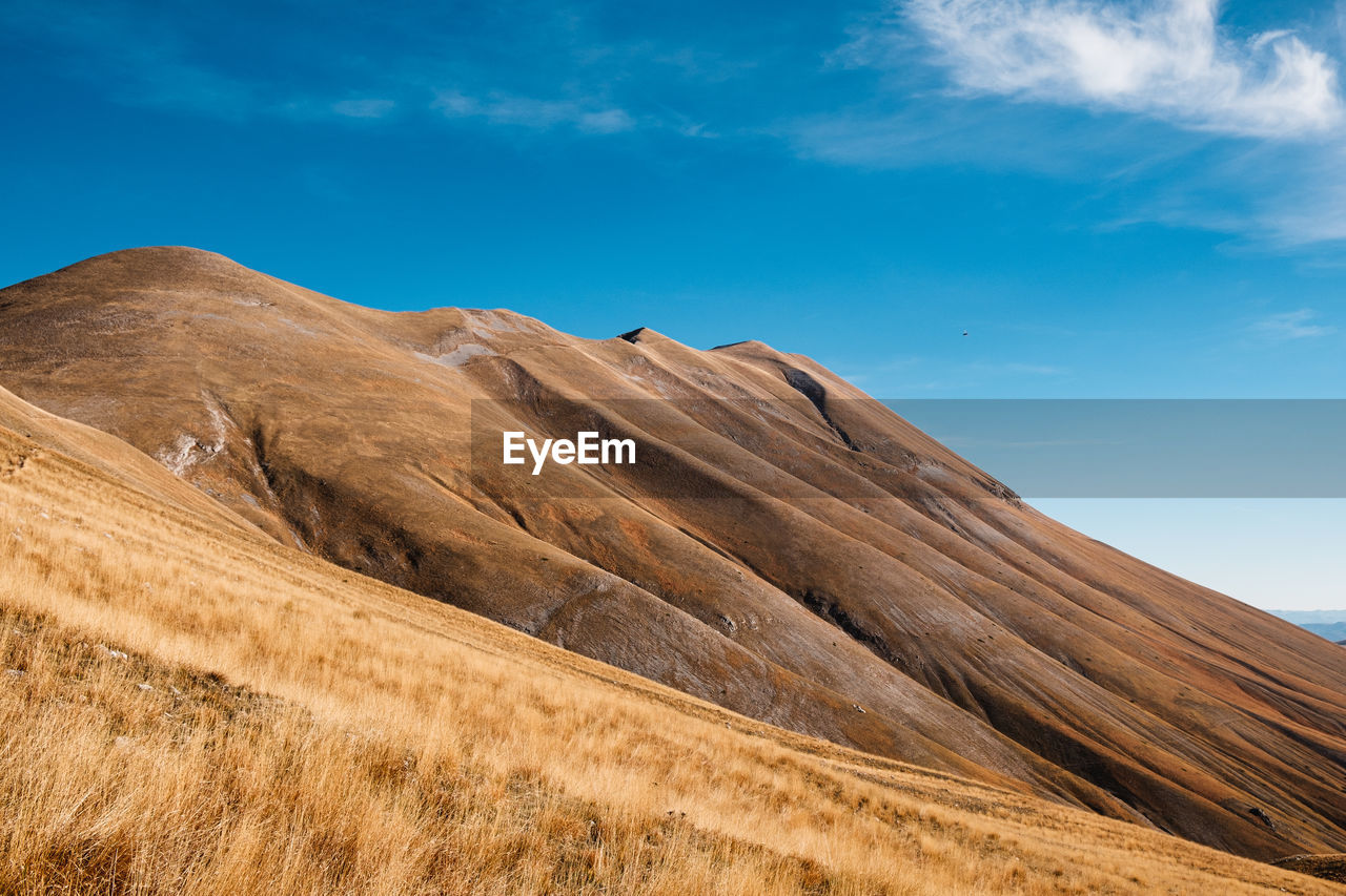 Low angle view of arid landscape against sky in castelluccio, umbria italy 