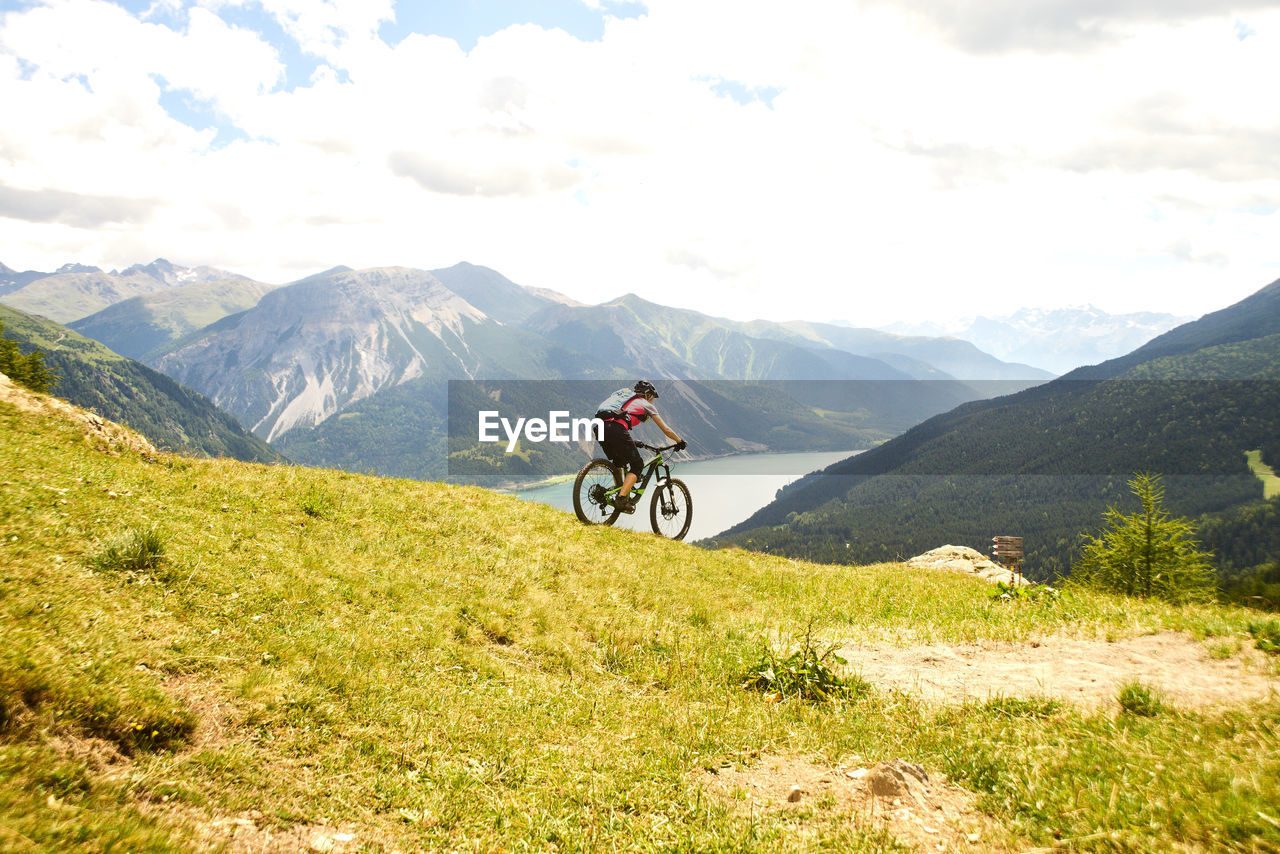 MAN RIDING BICYCLE ON MOUNTAIN ROAD