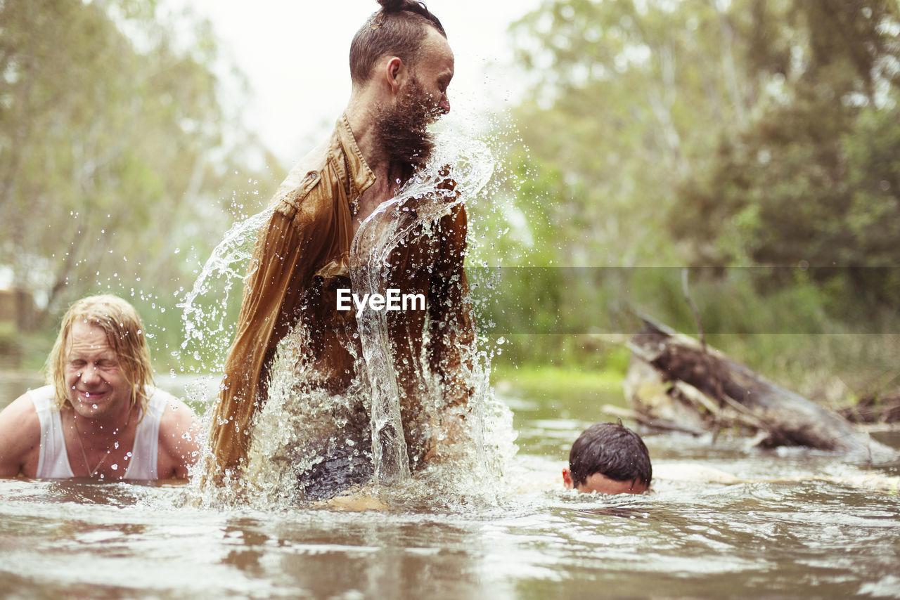 Happy friends bathing in river at forest