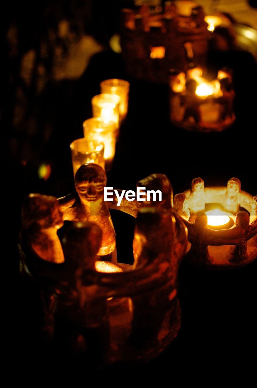 CLOSE-UP OF LIT TEA LIGHT CANDLE IN DARK ROOM