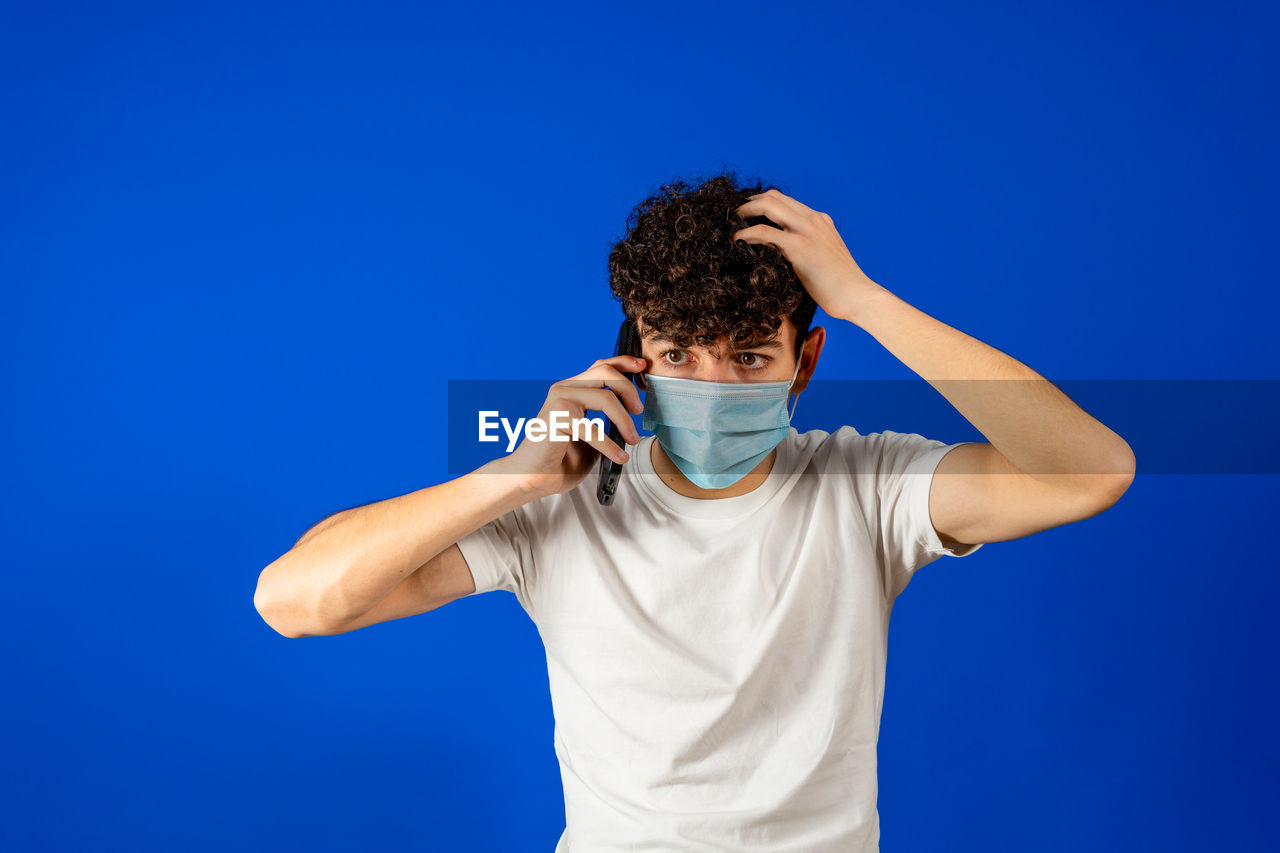 MAN STANDING AGAINST BLUE BACKGROUND