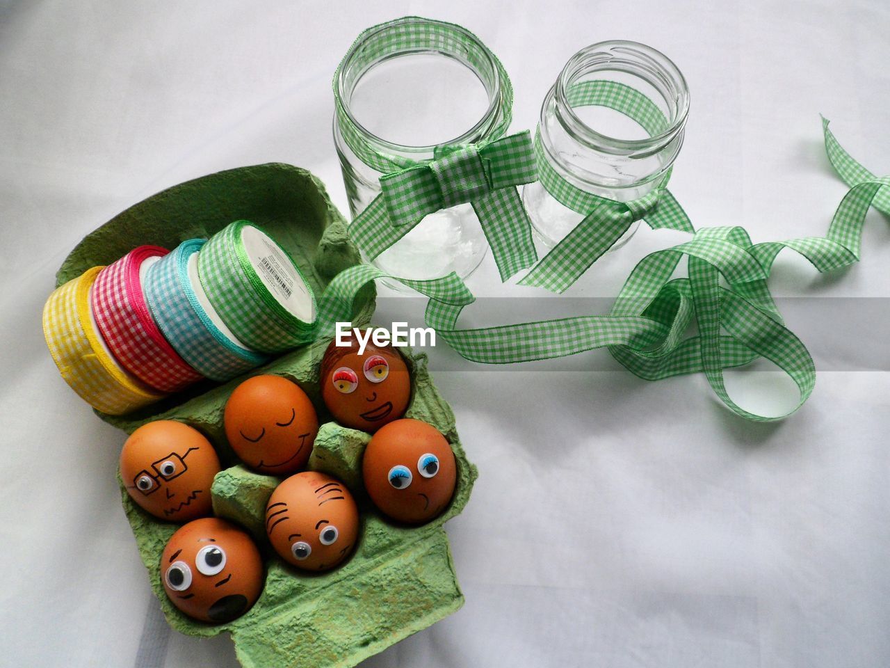 High angle view of eggs decorated on crate with ribbons and jars