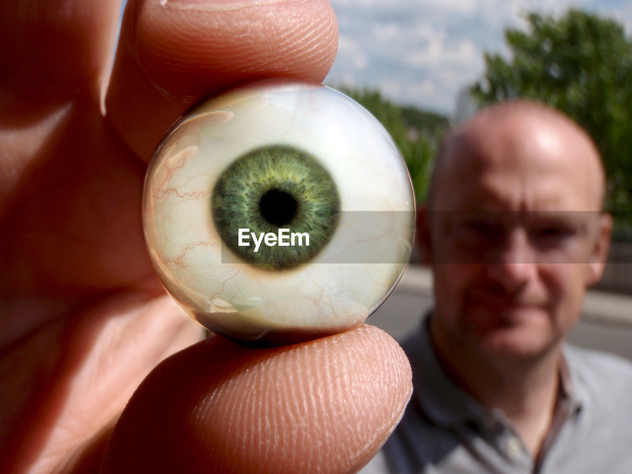 Close-up of man holding artificial eye