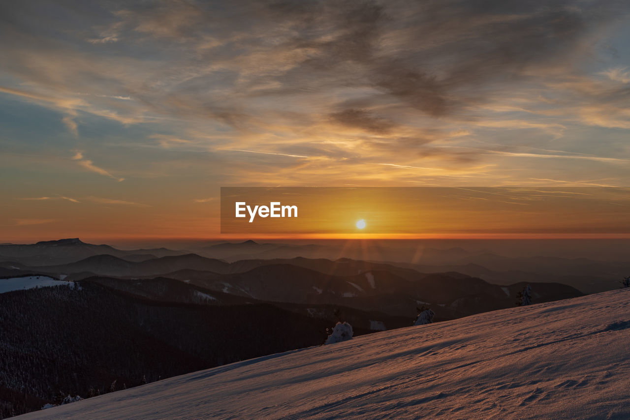 Scenic view of snowcapped mountains against sky during sunset