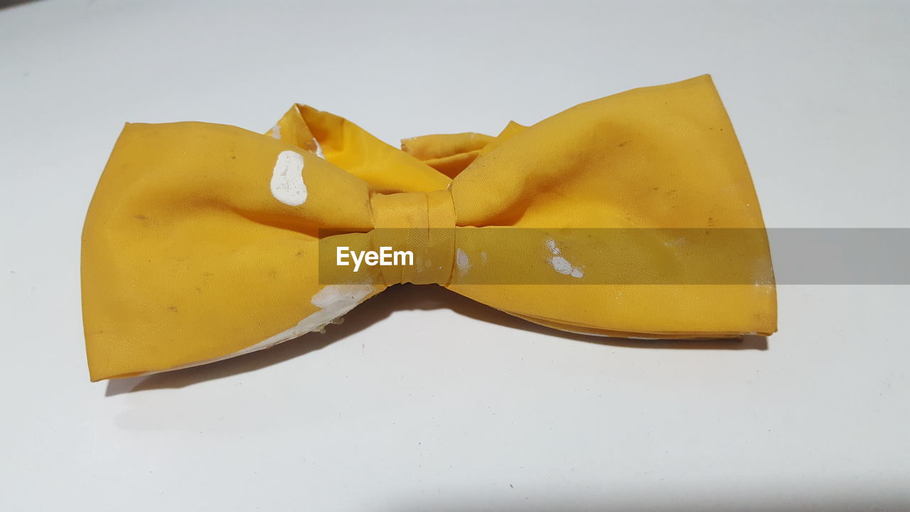 Close-up of yellow bow tie against white background