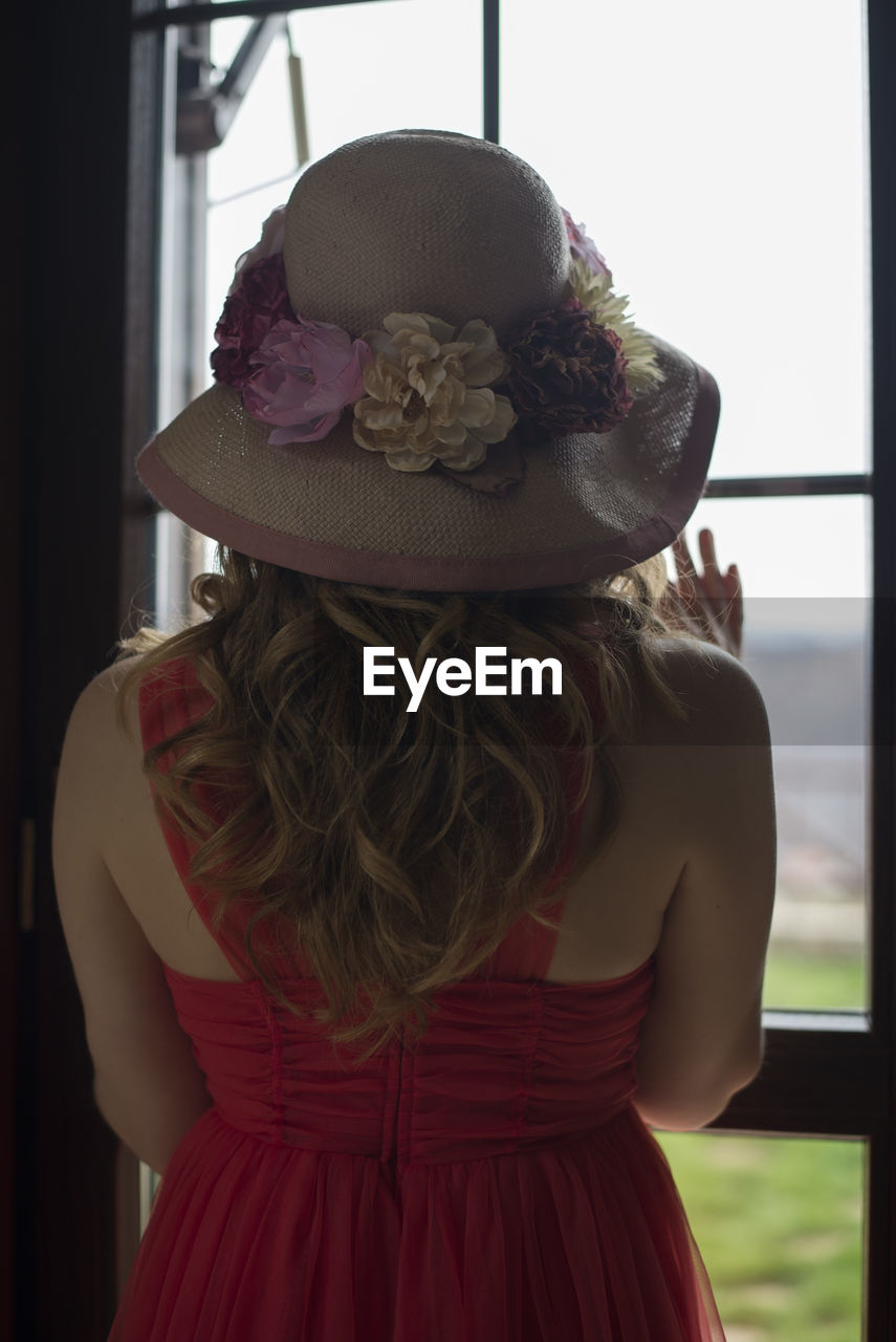 Rear view of woman in hat standing at home