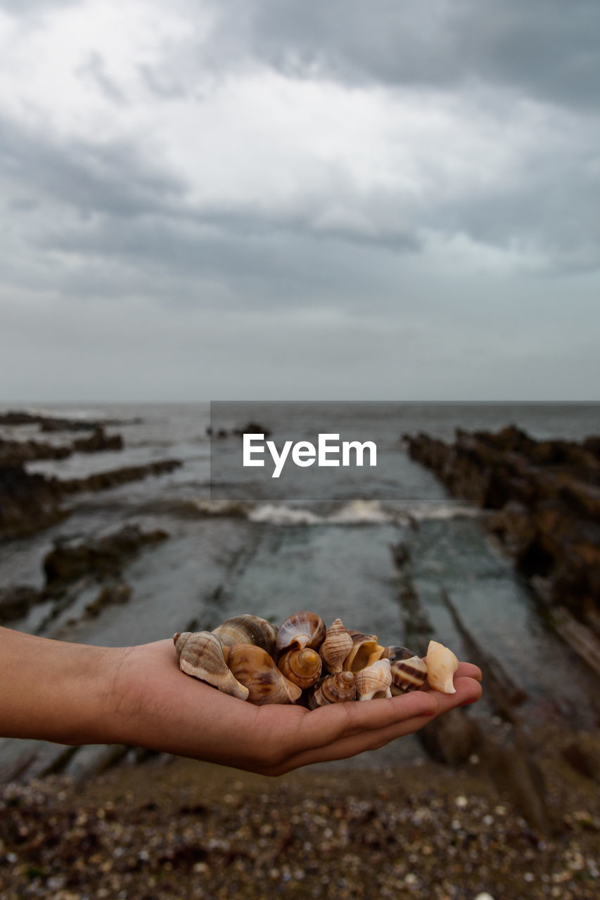 SCENIC VIEW OF PEBBLES ON BEACH AGAINST SKY