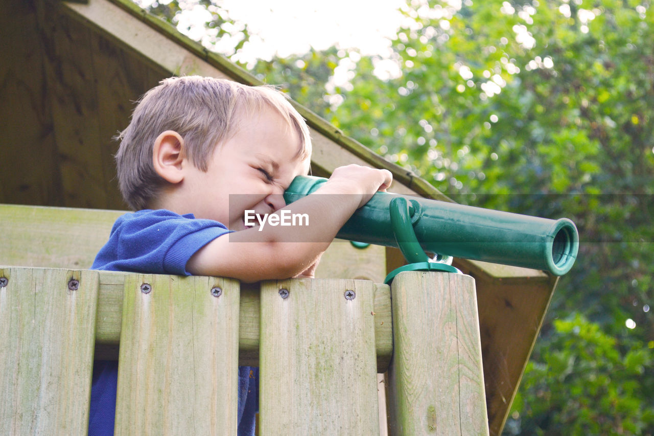 Boy looking through telescope in balcony