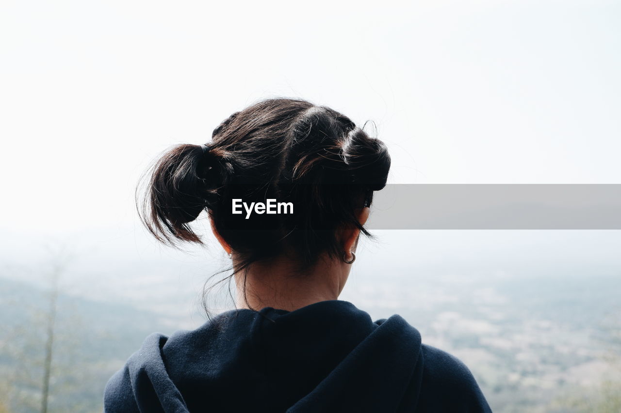 Rear view of woman looking at mountains against clear sky