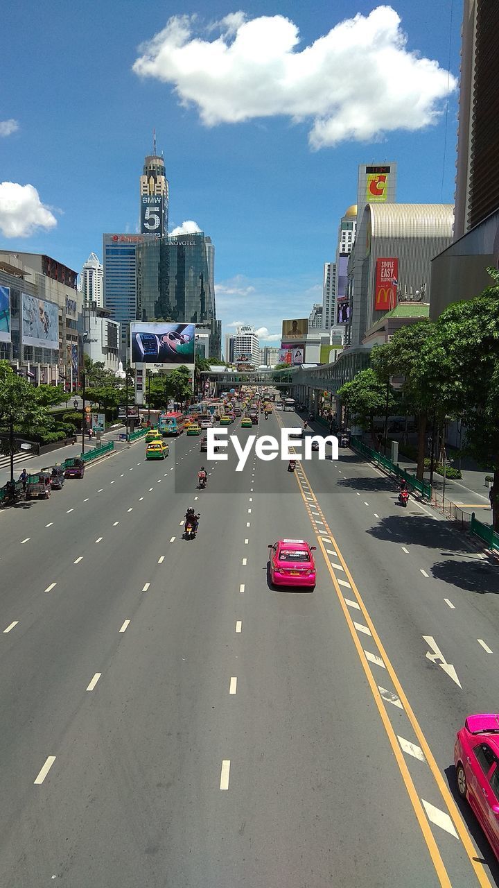 Vehicles on road against sky in city