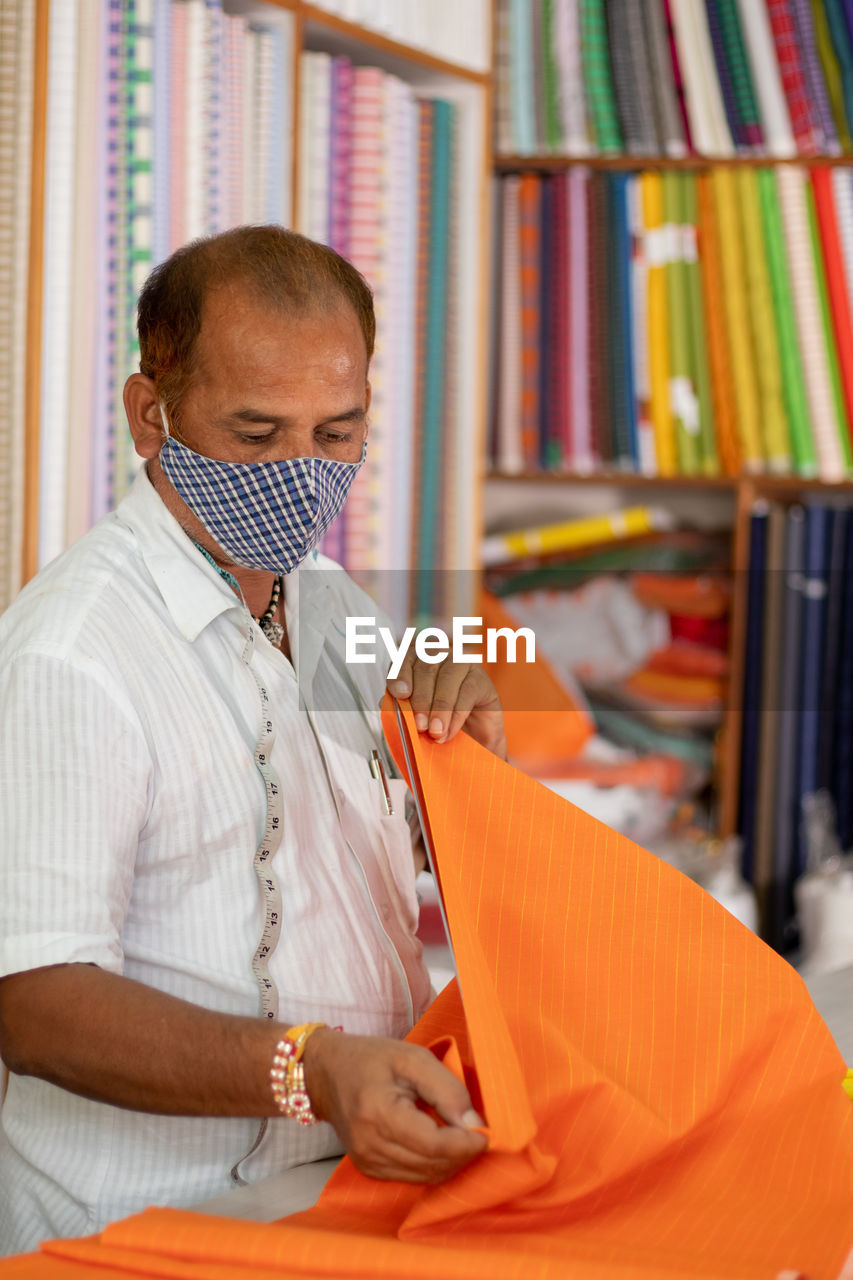 Tailor wearing protective face mask while working in shop