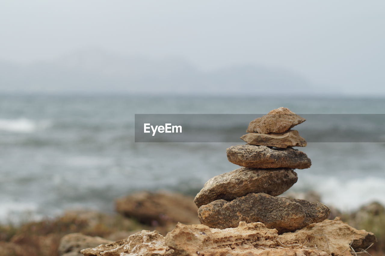 CLOSE-UP OF STACK OF PEBBLES ON BEACH