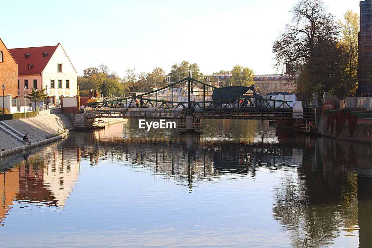 BRIDGE OVER RIVER BY BUILDINGS AGAINST SKY IN CITY