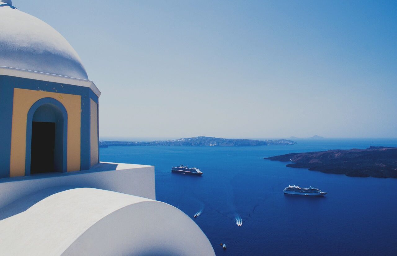 Cropped image of house by cruise ships sailing on sea against sky at santorini