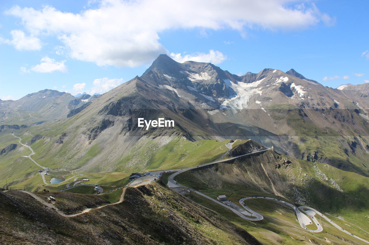 Scenic view of winding road in the mountains against cloudy sky