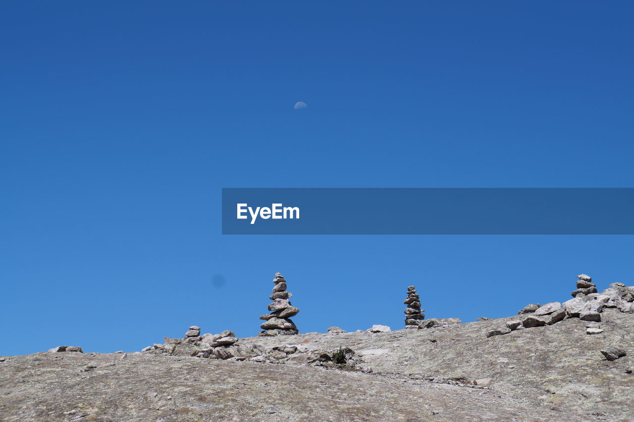 Low angle view of rocks against clear blue sky