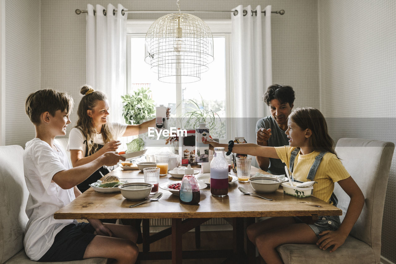 Parents having breakfast with children over table at home