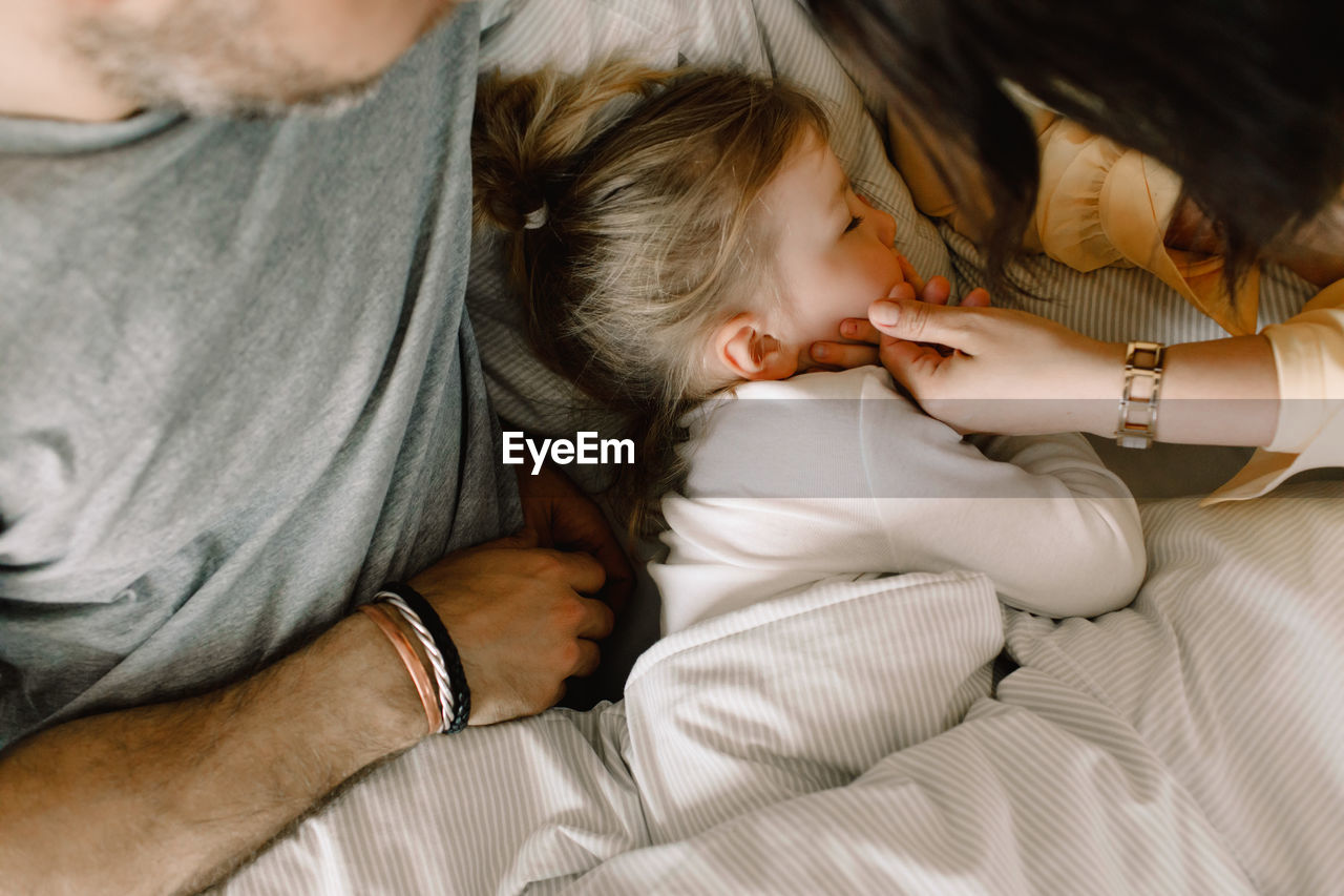 Directly above shot of girl sleeping with parents in bed at hotel