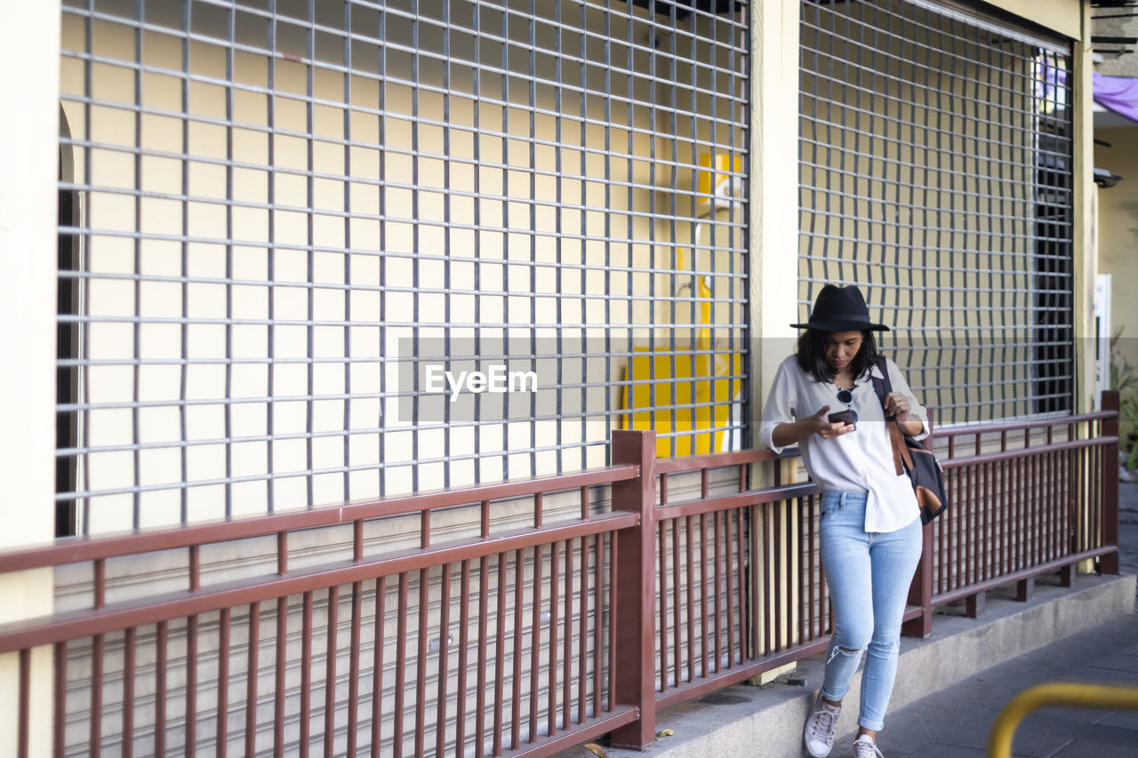 YOUNG WOMAN STANDING ON RAILING