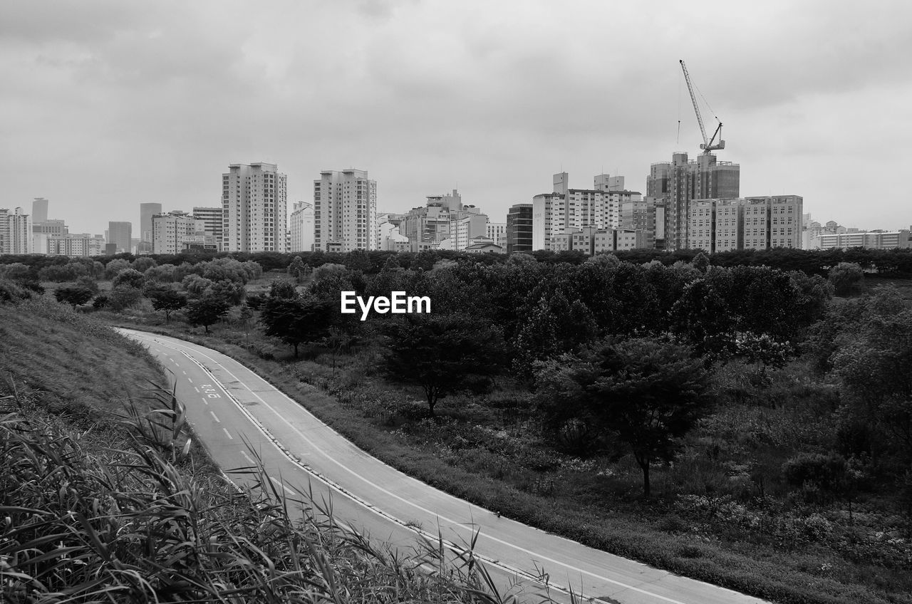 Road by buildings in city against sky