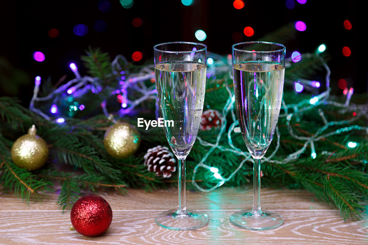 Close-up of champagne flutes by christmas decoration on table