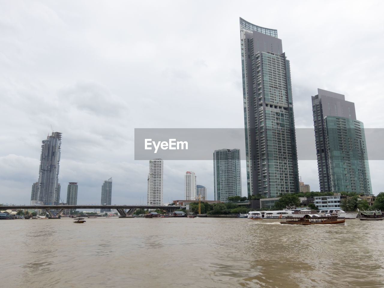 MODERN BUILDINGS BY RIVER AGAINST SKY