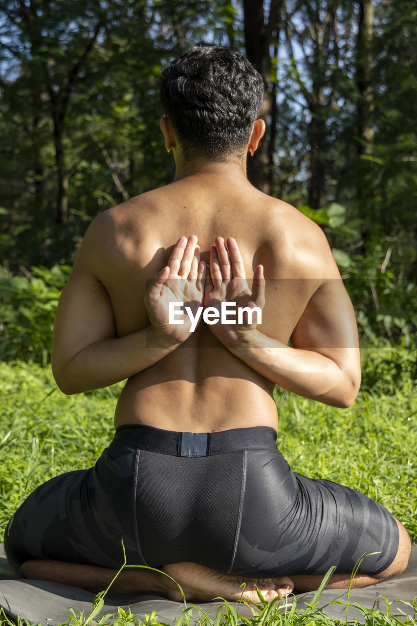Latin american man doing yoga posture, yoga posture, bee backwards prsthatah brahmara, forest