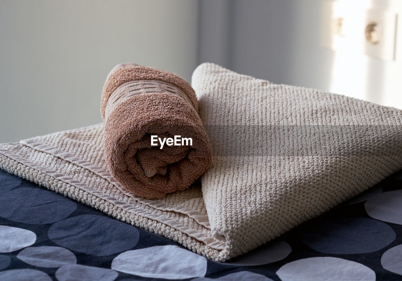 Close-up of rolled up towel on bed at home