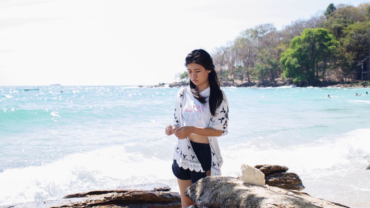 Woman standing by rock at beach