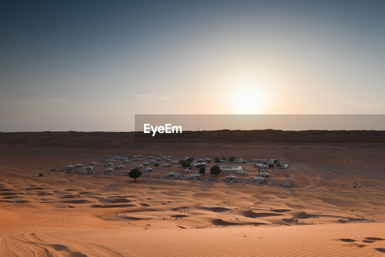 Buildings in desert against sky during sunset