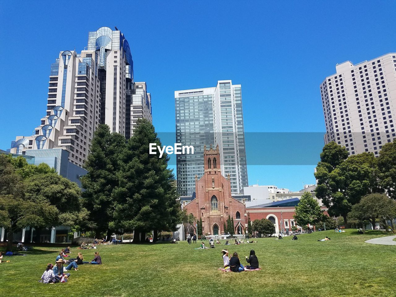 PEOPLE IN PARK AGAINST BUILDINGS IN CITY