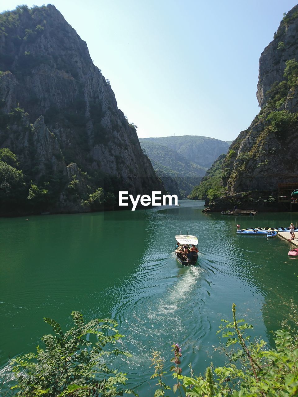 BOATS MOORED ON SEA AGAINST MOUNTAIN