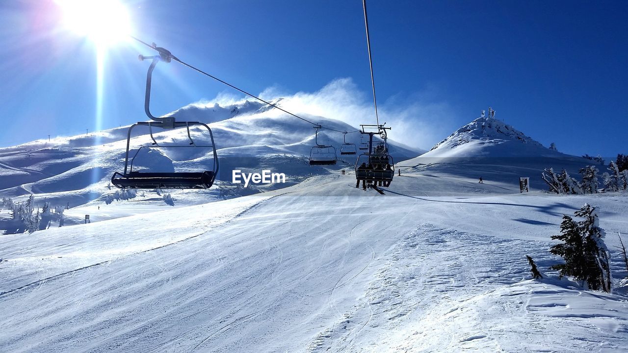 Ski lift on snowcapped mountains during sunny day