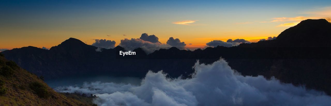 Panoramic view of clouds covered landscape and mountains at sunset