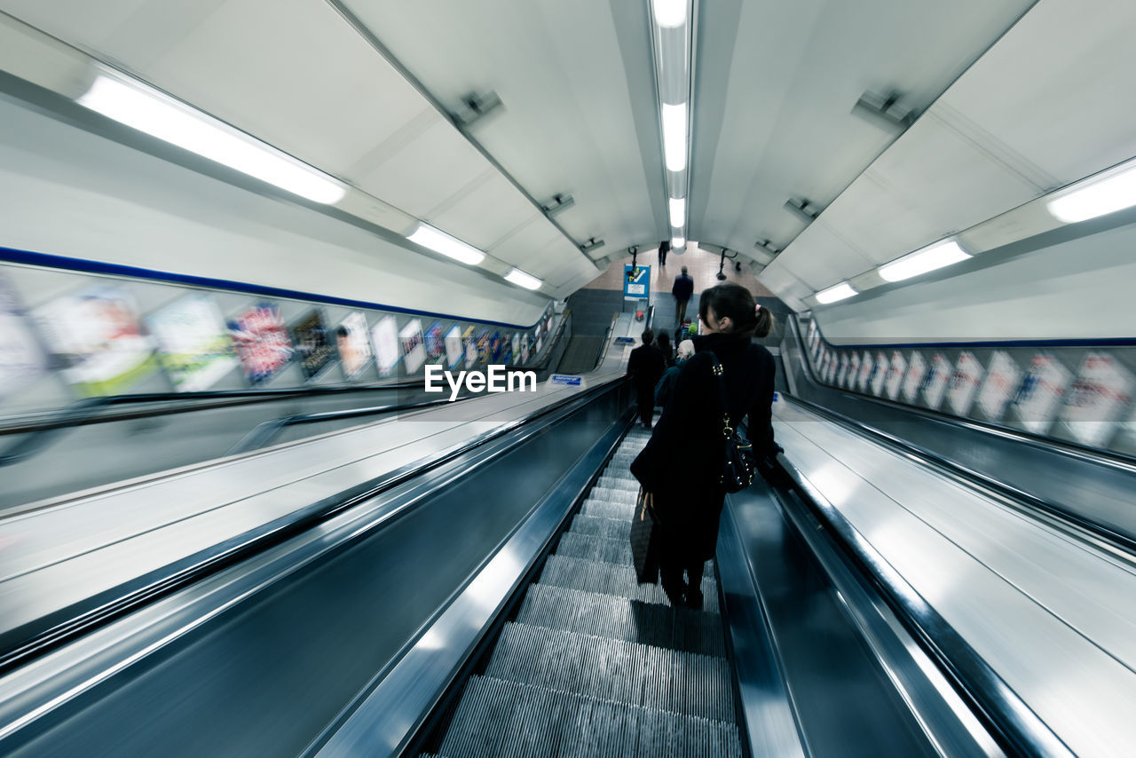 Rear view of people on escalators at subway station