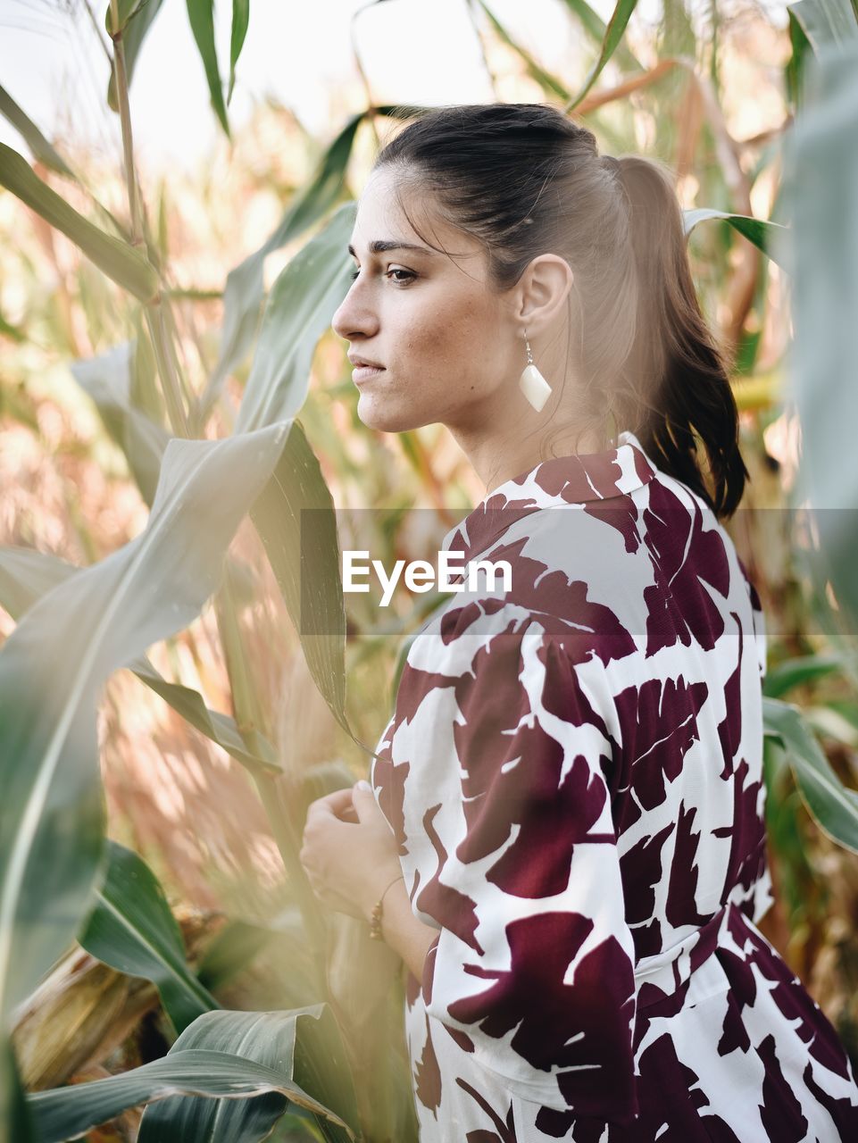 Side view of young woman looking at plants