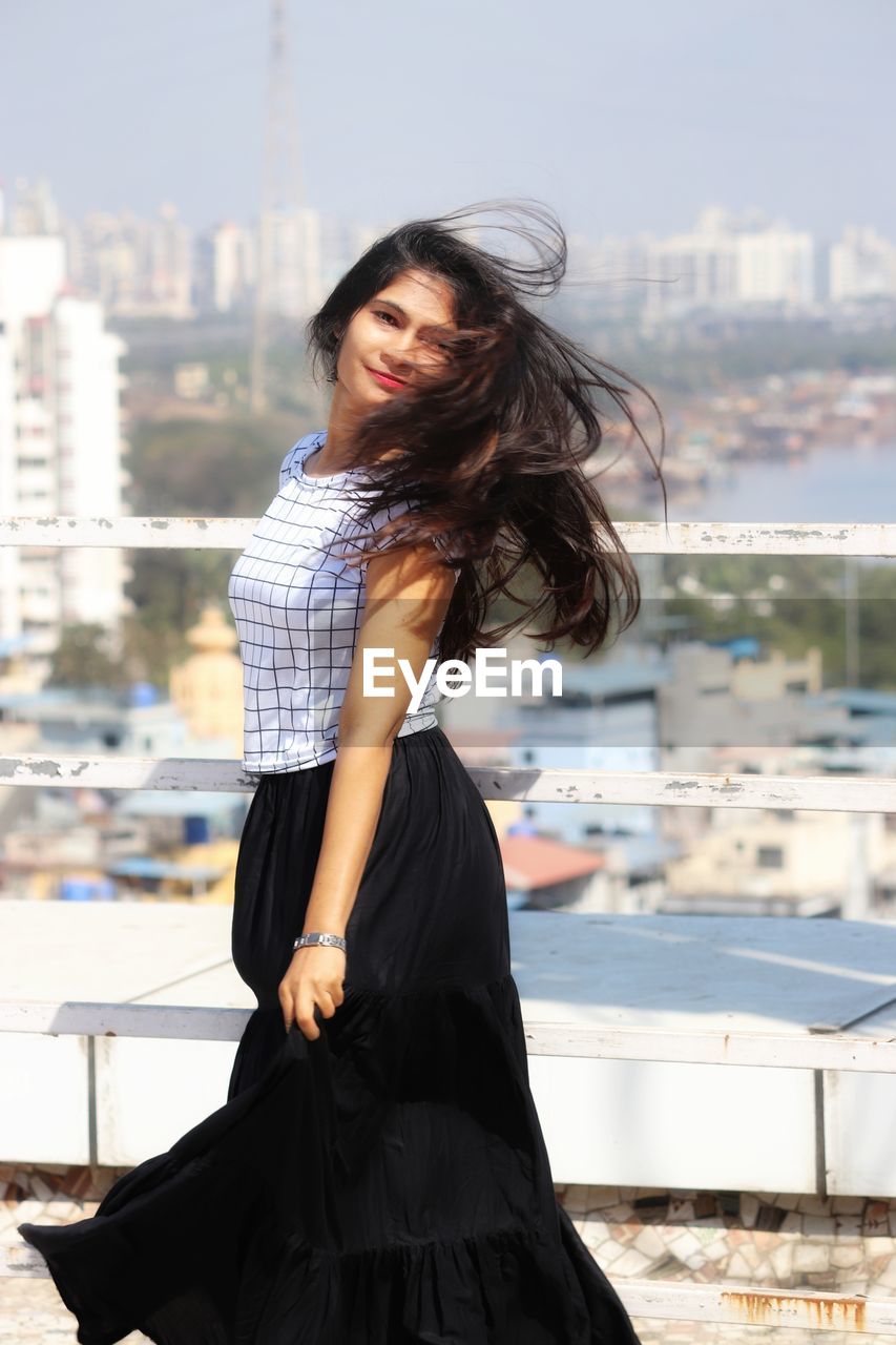 Beautiful young woman standing against cityscape in city