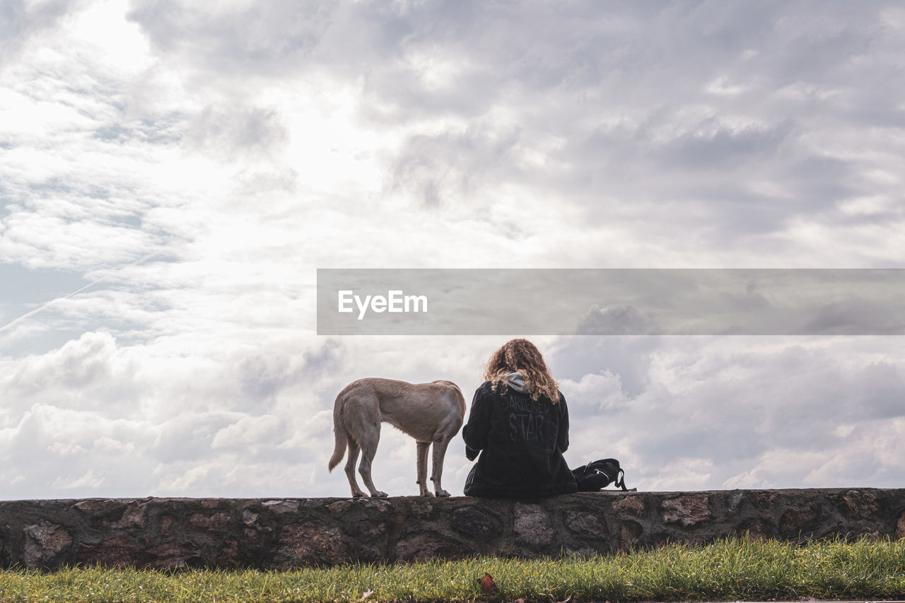 MAN SITTING WITH DOG ON FIELD