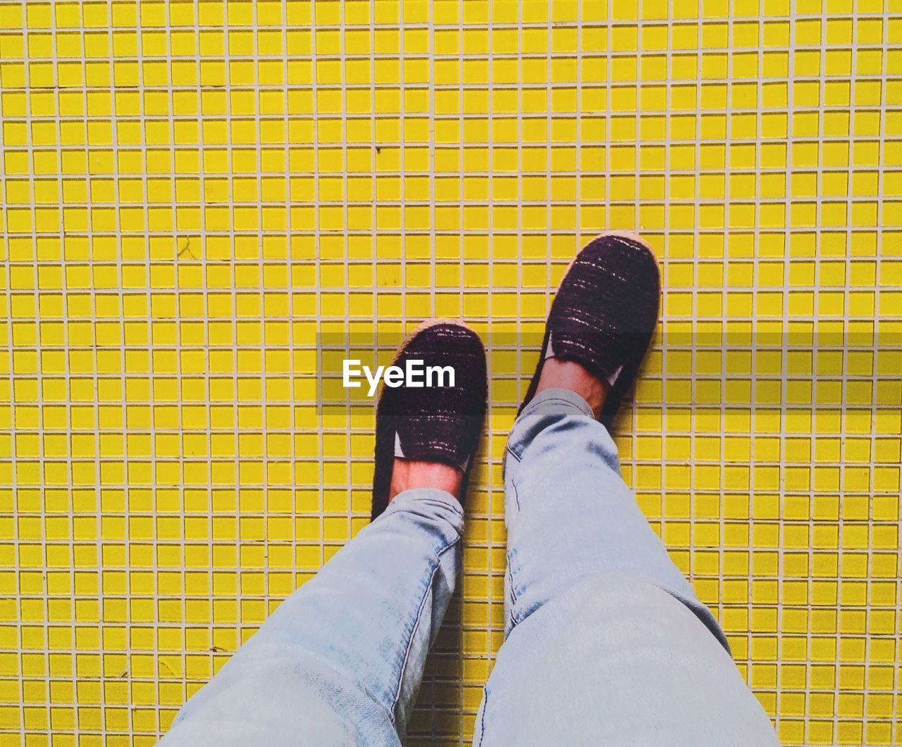 Low section of man standing on yellow tiled floor