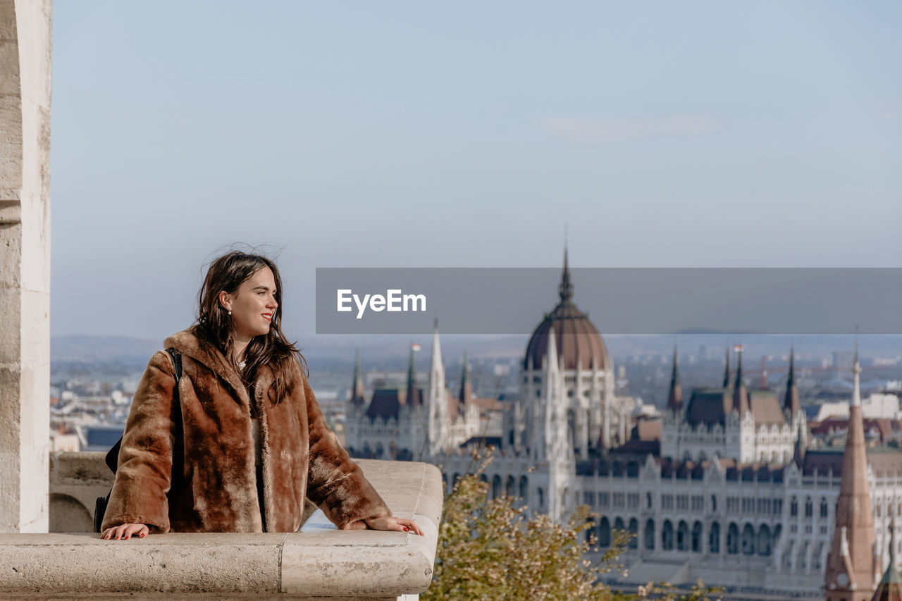 Portrait of girl standing on balcony overlooking city of budapest, hungary